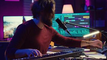 Artist singing a song at microphone and playing electronic piano to create music in home studio. Songwriter recording midi controller sounds, adjusting volume with pore amp knobs. Camera A. photo