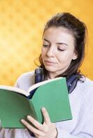 Smiling geek reading fantasy book, having fun and enjoying characters and plot, isolated over studio background. Relaxed bookworm reading fiction novel, enjoying leisure time, appreciating literature photo