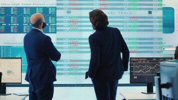 Business partners reviewing latest budgeting plans a big screen, sharing ideas and updates to ensure organizational progress. Forecast affiliates making decisions for a new fruitful project. Camera A. photo