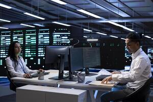 Teamworking technicians in server farm checking recovery plan, monitoring energy consumption. Team of engineers in data center making sure sensors are functioning optimally, doing routine disk checks photo
