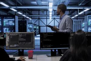 African american engineer doing yearly checkup to prolong data center electronics life span and avoid downtime. IT worker in server room monitoring server infrastructure components using tablet photo