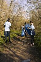 Environmental activist child gathering junk and plastic waste with a claw tool, recycling rubbish and clearing the forest. Young girl supporting ecology and zero waste activism. photo