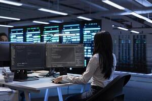 Programmer in data center checking equipment performance on computer after upgrading hardware. IT specialist doing checkup on storage devices and networking equipment in servers hub photo