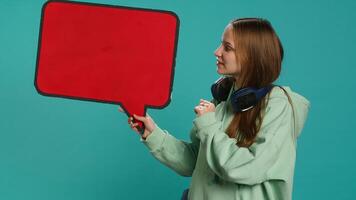 Smiling woman holding red speech bubble sign of empty copy space for message. Joyous teenager presenting thought bubble cardboard used as promotion concept, isolated over studio background, camera A photo