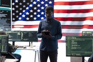 An American hacker in a governmental cyber defense room, showcasing advanced technology and hacking tools. Working on cybersecurity monitoring, digital security and national security. photo