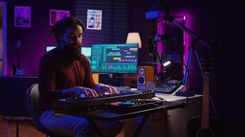 Sound engineer playing electronic piano keyboard and recording sounds, using mixing console and daw software to create new tunes. Music industry specialist uses stereo tools at home studio. Camera B. photo