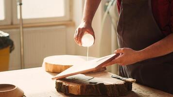 Woodworking specialist applying varnish on wood to build up protective layer. Cabinetmaker in assembly shop lacquering wooden board after sanding surface to ensure smoothness, close up shot, camera A photo