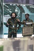 Professional army engineers gather intelligence for terrain operations, using surveillance CCTV footage in military power base. Soldiers examining important real time data on a big screen. photo