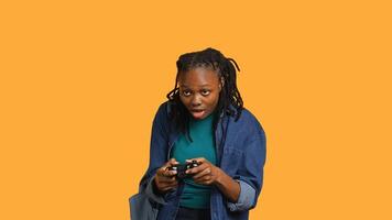 Euphoric african american woman playing intense gaming console game, celebrating win, studio background. Ecstatic young girl using controller, excited after being victorious in videogame, camera A photo