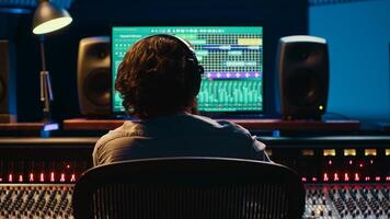 Using audio editing software, sound producer creates tunes and handling technical equipment on a control room dashboard. Technician music producer increases tracks quality. Camera A. photo