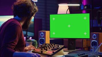 Audio engineer learning to mix piano notes with mixing console, watches online lesson tutorials on greenscreen monitor display. Music producer creating soundtracks, learns editing skills. Camera A. photo