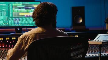 Audio technician working in control room to edit and process tracks, using audio software on pc for music industry post production. Skilled producer creating tunes with mixing console. Camera A. photo