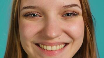 Extreme close up shot of elated joyful girl smiling, having fun, isolated over backdrop. Portrait of relaxed radiant woman grinning, having positive facial expression and good mood photo