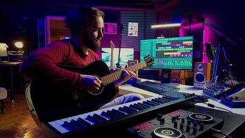 Music producer playing guitar to create tunes and mix them after, having fun with musical instrument and amplifier at his home studio. Talented artist songwriter composing a new track. Camera A. photo
