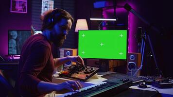 Music producer songwriter mixing piano key notes in home studio, operating with greenscreen monitor on pc. Artist producing sound effects and adjusting volume levels with electronic tools. Camera B. photo