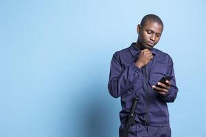 Security agent browses smartphone apps to check text messages, using social media accounts to chat with his friends during his job duty. Trained guard checks websites online in studio. photo