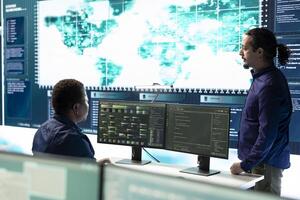 Group of governmental hackers using hacking tools to secure a network, focusing on cyber defense and data protection measures. Experts team examining important information on big screen. photo