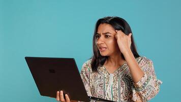 Irked woman fighting with coworkers during videocall on laptop, isolated over studio background. Outraged person arguing with colleagues during conversation on notebook, camera B photo