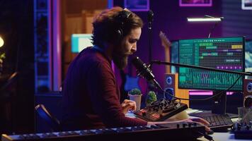 Sound engineer recording backing vocals and singing on microphone, using daw software and mixing console in home studio. Artist listening to mixed tracks and create a good acoustic audio. Camera A. photo