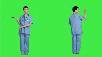Healthcare specialist presenting a thing for promotional ad in studio, pointing at something against greenscreen backdrop. Medical assistant creating a web commercial, health expertise. Camera A. photo