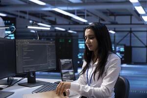 Data center specialist developing emergency procedures to ensure business continuity in case of disaster or system failure. Woman in server farm ensuring compliance with industry regulations photo