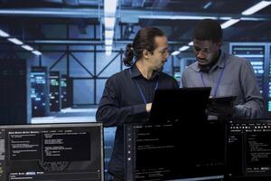 Teamworking admins in server farm checking recovery plan, monitoring energy consumption. Coworkers in data center workspace making sure sensors are functioning optimally, doing routine disk checks photo