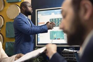 Office administrator showing statistics on interactive board in a meeting, conference with workers for a presentation. Colleagues studying sales data to adapt within market conditions. photo