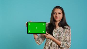 Energetic salesman doing influencer marketing using green screen tablet, studio background. Lively woman reviewing product, holding empty copy space mockup digital device, camera A photo