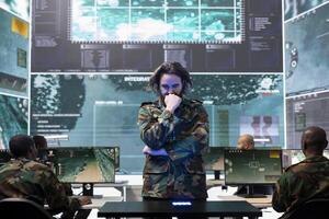 Young army conscript checking mission data and details on a hologram projection, studying operation briefings in military command center. Soldier looks at CCTV radar imagery on 3d visualization. photo