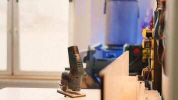 Chisels, screwdrivers, wrench and pliers on wall in furniture assembly shop next to electric router on workbench. Close up of woodworking gear on rack in joinery and power tool photo