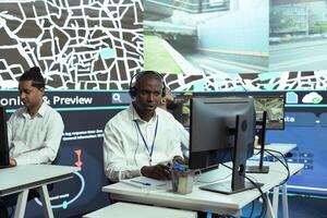 African american man offers updates to clients via order tracking service, monitoring delivery trucks through city traffic and providing gps coordinates. Dispatch employee in control center. photo