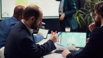 Accounting experts studying sales trends and market demands to ensure project success, looking into data infographics in executive meeting. Financial department team reviews revenue funds. Camera A. photo