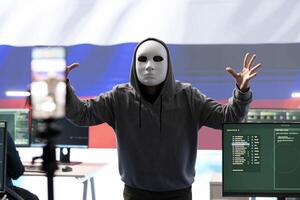 Anonymous hacker expert in a russian hacking high tech office, digital threats and political espionage. Inflicting cyber terror, propaganda and crisis management in information war. photo