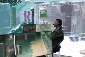 Woman IT operator analyzing real time battlefield data on big screen, collecting information for a reconnaissance mission. Military personnel provides air support to infantry unit in the field. photo