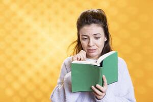 Woman sobbing while reading sad book, enjoying hobby during leisure time. Bookaholic person with novel in hands weeping, enthralled by emotional story, isolated over studio background photo