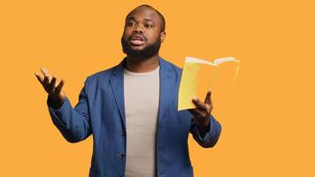 Man reading book aloud, narrating story for audience, doing monologue for theatre play. Person rehearsing using literature novel source material, reciting from pages, studio background, camera A photo
