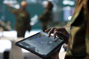 Trooper monitoring the operational area via CCTV surveillance footage, using a tablet to find any threats in command post power base. Anti terrorism army division headquarters. Close up. photo