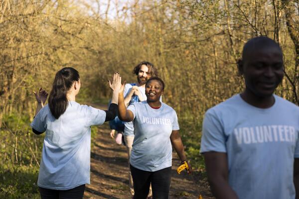 Joyful group of environmentalists doing high five with each other, saying congratulations and being satisfied with their teamwork efforts. Leader praising her colleagues, resilience.