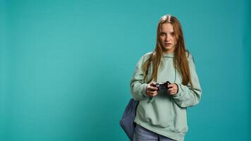 Young girl spamming controller buttons, disappointed after receiving game over screen. Woman upset after losing videogame, playing with gamepad, studio background, camera B photo