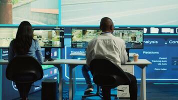 Diverse employees working on examining real time surveillance footage to find irregularities within urban traffic dynamics. Agency workers monitoring on CCTV system for intelligence. Camera A. photo