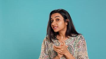 Portrait of jealous indian woman mockingly clapping hands, isolated over studio background. Annoyed person rolling eyes and applauding in jest, doing fake cheering, camera B photo