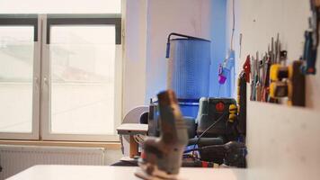 Electric router with woodworking tools on rack in background in workshop. Focus on hand powered equipment in front of chisels, screwdrivers, on wall in carpentry studio, panning shot photo
