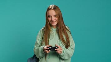 Young gamer girl holding controller, focused on finishing difficult videogame level. Woman gaming with gamepad and solving quests, isolated over studio backdrop, camera A photo