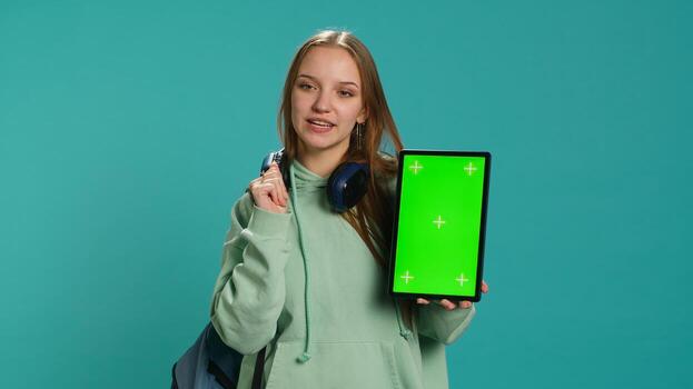 Portrait of woman presenting tablet with chroma key display, isolated over studio background. Young girl creating promotion with blank copy space mockup digital device, camera A photo