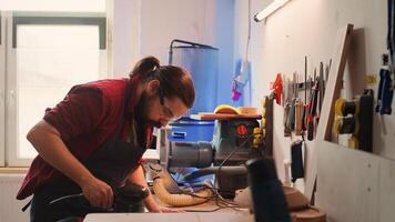 African american carpenter in joinery watching apprentice using orbital sander on lumber. Team in woodworking shop using angle grinder to create wooden decorations, refining wood objects, camera B photo