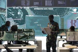 Special operations engineer reading new mission case file brief in control room, working with real time surveillance projection on a big screen. Trooper in army division defense program. photo