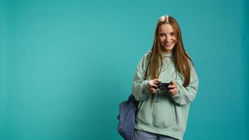 Young gamer girl holding controller, focused on finishing difficult videogame level. Woman gaming with gamepad and solving quests, isolated over studio backdrop, camera B photo