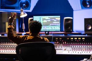 Sound designer counting down for artist to sing in sound booth, showing a sign to let the singer know when to start the performance. Music producer operating control desk panel board. photo