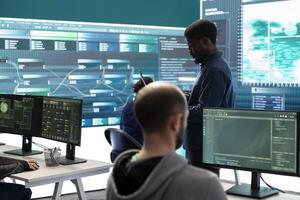 Governmental hackers breaching network security with advanced techniques, cyber defense in action. Team of IT experts working on gaining access to collect information, big screen. photo