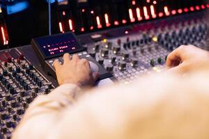 Tracking engineer pressing faders and buttons on control desk to balance sounds and add effects in post production, creating new music. Technical expert working with sliders in professional studio. photo
